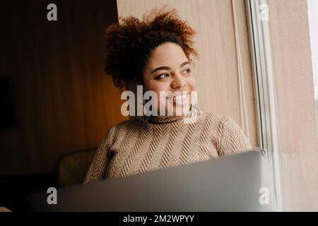 Young beautiful happy smiling african woman with laptop looking rightward Stockfoto