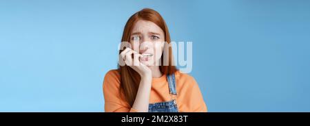 Intensiv besorgt Angst unsicher junge Rotschopf panisch dumme Mädchen runzelte die Stirn Schauen aufgeregt ängstlich beißen Fingernägel emotional erschrocken gefeuert stehend Stockfoto