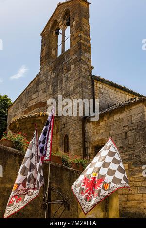 Braune und weiße Flaggen an der Kirche Santa Maria Assunta, San Quirico dOrcia, Toskana, Italien Stockfoto