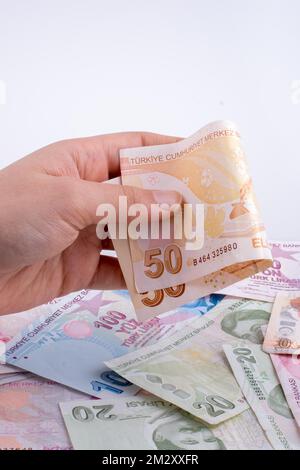 Hand mit Turksh Lira-Banknote auf weißem Hintergrund Stockfoto