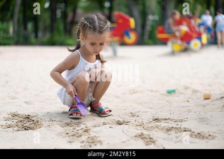 Kleines Mädchen Spielt Sandbox Spielplatz Graben Sand Schaufel Gebäude Sandfigur Sommertag. Kaukasische weibliche Kind 5 Jahre haben Spaß im Freien Stockfoto