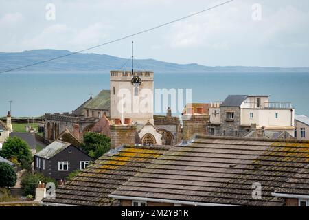 Blick auf die Kirche St. Michaels Lyme Regis Dorset England auf Dächern mit Meer im Hintergrund Stockfoto