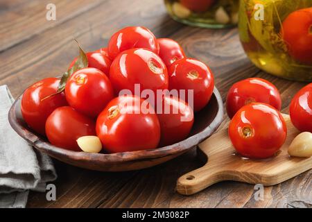 Hausgemachte eingelegte Tomaten. Schüssel mit Tomatenkonserven. Mariniertes Gemüse in Glasgefäßen im Hintergrund. Stockfoto