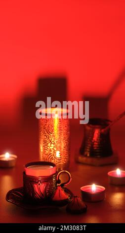 Türkische Kaffeekanne und traditionelle Tasse mit orientalischen Süßigkeiten. Metalllaterne, kunstvolle Girlande und Teelichter. Viva Magenta, Farbe des Jahres 2023. Rot Stockfoto