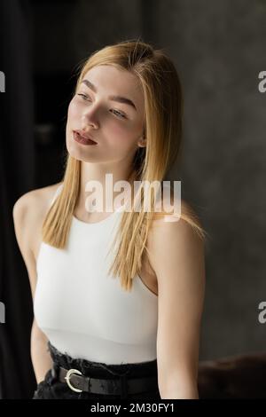 Blonde Frau mit weißem Oberteil, die nach Hause blickt, Stock Image Stockfoto