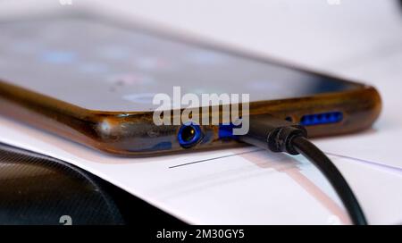 Nahaufnahme des alten android-Smartphone-Ladeanschlusses mit usb-C-Kabel. Stockfoto