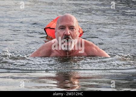 London, Großbritannien. 14.. Dezember 2022. Schwimmer Bernd ist gekommen, um zu schwimmen und erstickt das Wasser mit einem Lächeln. Schwimmer trotzen dem kalten, aber sonnigen Wetter und schwimmen im offenen Wasser im Beckenham Place Park Swimming Lake, einem See in natürlicher Umgebung im Beckenham Place Park im Südosten Londons. Zwei voll ausgebildete Rettungsschwimmer sind anwesend mit Rettungsausrüstung für die gebuchten Schwimmgänge im offenen Wasser und alle Schwimmer hatten Einführungssitzungen zum Schwimmen im Winter und Sicherheitsmaßnahmen und schwimmen mit einer Rettungsboje. Kredit: Imageplotter/Alamy Live News Stockfoto