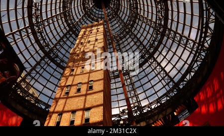 Coop's Shot Tower ist ein Turm im Herzen von Melbourne CBD, Australien. Es wurde 1889 fertiggestellt und ist 50m m hoch. Das historische Gebäude wurde 1973 vor dem Abriss bewahrt und 1991 unter einem 84 m hohen konischen Glasdach in den Melbourne Central Komplex integriert. Ein Turm ist ein Turm, der für die Herstellung von Kugeln mit kleinem Durchmesser durch freien Fall von geschmolzenem Blei ausgelegt ist, das dann in einem Wasserbecken gefangen wird. Die Aufnahme wird hauptsächlich für Projektile in Schrotflinten sowie für Vorschaltgeräte, Strahlenschutzschirme und andere Anwendungen verwendet, bei denen kleine Bleikugeln nützlich sind. Stockfoto