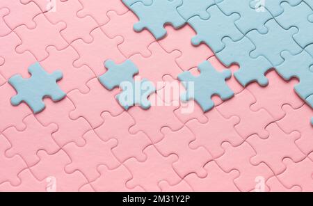 Blaue Puzzles und pinkfarbene Puzzles mit separaten Elementen. Hochwertiges Foto Stockfoto
