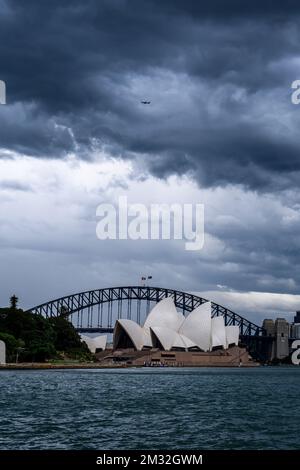 Eine vertikale Aufnahme stürmischer Wolken über dem Opernhaus von Sydney und der Harbour Bridge. Stockfoto