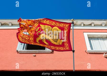 Löwenflagge von Venedig, Blick auf eine Flagge des Löwen des Heiligen Markus - Wahrzeichen der Stadt und der Comune von Venedig - in einer Straße auf der venezianischen Insel Chioggia. Stockfoto