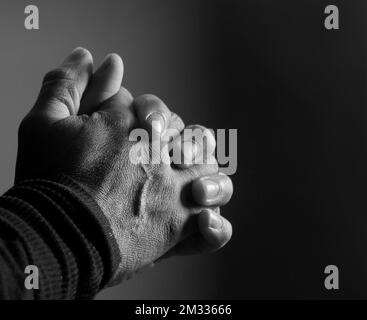 Ein Mann betet mit Händen zu gott, mit Hintergrund und Stammfotos Stockfoto
