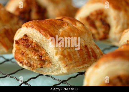 Frisch gebackene, hausgemachte vegetarische Wurstbrötchen mit Käselaibe, Zwiebeln und Brotkrumen, die auf einem alten Kühlregal aus Draht gekühlt werden Stockfoto