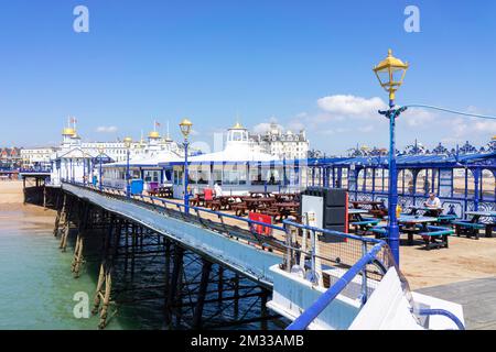 Eastbourne East Sussex blickt zurück entlang des Piers zu Menschen, die an Cafetstischen am Eastbourne Pier Eastbourne East Sussex England GB Europe saßen Stockfoto