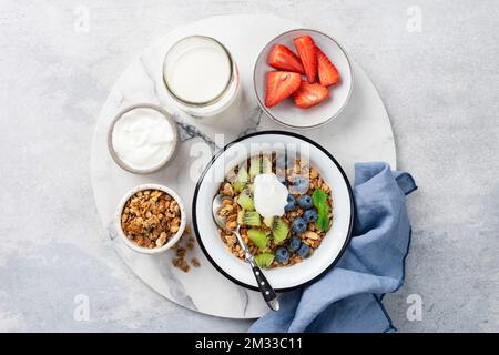 Müsli mit Obst und Joghurt in einer Schüssel. Tabellenansicht. Süße Frühstückszerealien Stockfoto