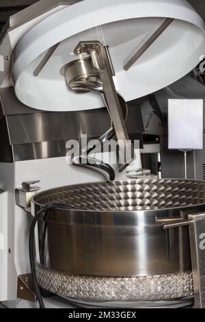 Ein Fragment einer Spiralmischschüssel aus Edelstahl für die Lebensmittelindustrie zur Zubereitung einer großen Menge Teig. Stockfoto