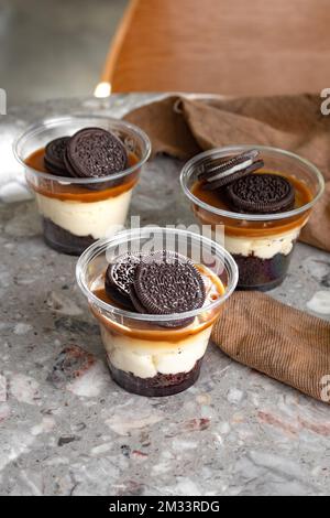 Mini-Desserts, Snacks in Plastikbechern. Auf dem Tisch Käsekuchen zum Mitnehmen Stockfoto