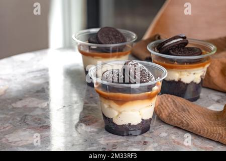 Mini-Desserts, Snacks in Plastikbechern. Auf dem Tisch Käsekuchen zum Mitnehmen Stockfoto