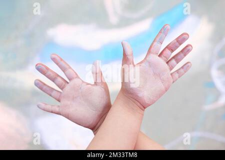 Kinderhände gefärbt mit farbiger Kreide isoliert auf abstrakter Zeichnung. Nahaufnahme. Selektiver Fokus. Stockfoto