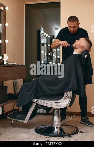 Friseur rasierender Weißer im Friseursalon Stockfoto