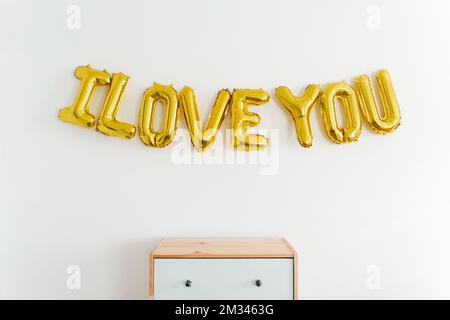 Inschrift Ich LIEBE DICH, aufblasbarer Goldballon aus Folie an der Wand. Konzept für Liebe, Romantik und Valentinstag. Flach liegend mit Kopierbereich Stockfoto