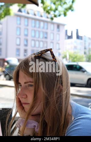 Junge Frau langweilt sich in einem Straßencafé Stockfoto