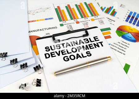 Geschäftskonzept. Auf der Tabelle unter den Finanzgrafiken und -Diagrammen befindet sich eine Tafel mit der Aufschrift „Nachhaltige Entwicklungsziele“ Stockfoto