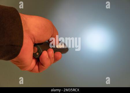 Taschenlampe mit LED in der Hand. Leuchtet auf blauem Hintergrund. Speicherplatz kopieren Stockfoto