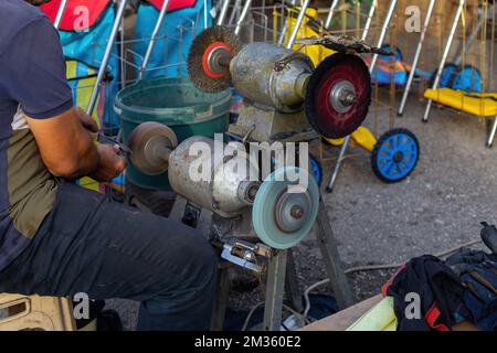 Ein Mann, der auf dem Markt ein Messer schärft. Metallmesser Stockfoto