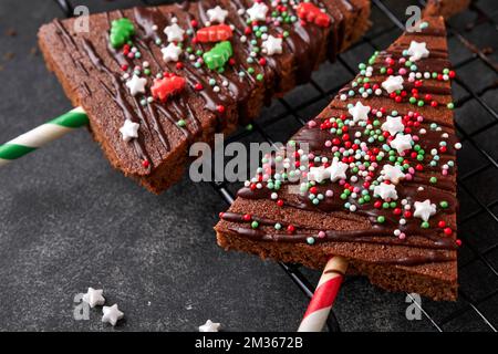 Schokoladen-Brownies-Weihnachtsbaum mit Schokoladeneis und festlichen Streuseln auf einem Steintisch. Ideen für Weihnachtsessen süße hausgemachte Weihnachtsferien Pa Stockfoto
