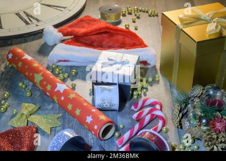 Wir bereiten uns auf Weihnachten vor. Attribute für Geschenke, farbige Bänder, Geschenkboxen, Geschenkpapier auf einem Holztisch Stockfoto