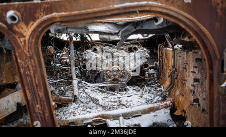 Mirolybivka, Region Kherson, Ukraine - 12.07.2022: Der Motor abgebrannter gepanzerter Fahrzeuge der russischen Armee im Schnee in Weiß, Grau und Rot Stockfoto