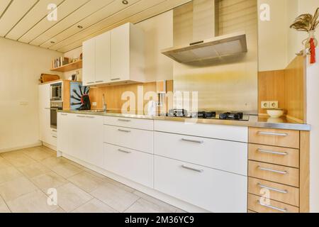 Eine moderne Küche mit weißen Schränken und Holzablageflächen auf den Ablagen in diesem Zimmer ist sehr sauber, aber das ist es nicht Stockfoto