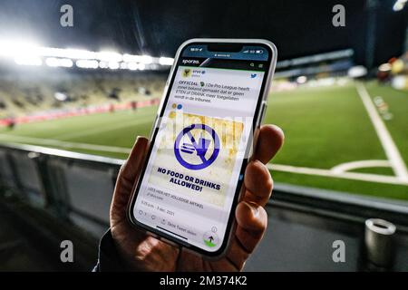 Das Bild zeigt eine Person, die ein Mobiltelefon zeigt, und zwar mit einem Hinweis des STVV twitter-Kontos, dass während des Spiels vor einem Fußballspiel zwischen Sint-Truidense VV und Royale Union Saint-Gilloise, Freitag, den 03. Dezember 2021 in Sint-Truiden, keine Getränke oder Speisen erlaubt sind. Am 17. Tag der ersten Runde der belgischen Meisterschaft 2021-2022 in der „Jupiler Pro League“. BELGA FOTO BRUNO FAHY Stockfoto