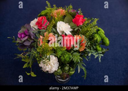 Blumenstrauß aus roten Gerberas, Nelken und Grün in einer Glasvase, professionell hergestellt Stockfoto