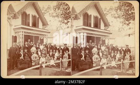 Group portrait of thirty-six people seated and standing in front of cottages , Dwellings Stock Photo