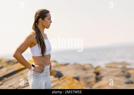 Betrachtete Fit-Frau, Die Mit Den Händen An Der Hüfte Steht Stockfoto