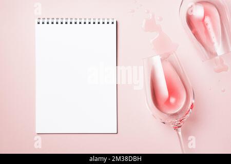 Zwei Gläser Rosenwein und ein Blatt Papier auf pinkfarbenem Hintergrund, Draufsicht. Stockfoto
