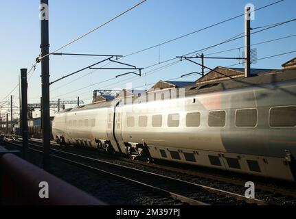 Sonnenlicht reflektiert an der Seite des Avanti West Coast pendolino Zuges, der am 14.. Dezember 2022 auf der West Coast Main Line durch Carnforth fährt. Stockfoto