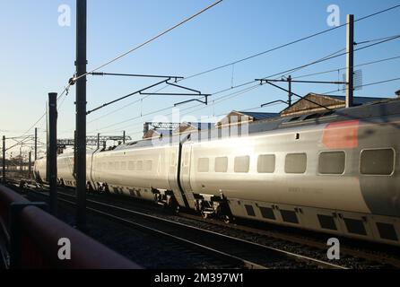 Sonnenlicht reflektiert an der Seite des Avanti West Coast pendolino Zuges, der am 14.. Dezember 2022 auf der West Coast Main Line durch Carnforth fährt. Stockfoto