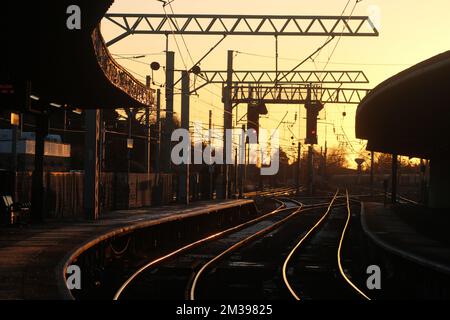 Keine Züge am Streiktag am 14.. Dezember 2022. Sehen Sie die leere Strecke bei Carnforth bei Sonnenuntergang mit allen Lichtern an der Signalgantry bei Rot. Stockfoto