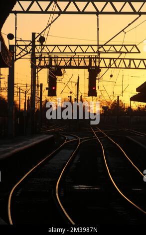 Keine Züge am Streiktag am 14.. Dezember 2022. Sehen Sie die leere Strecke bei Carnforth bei Sonnenuntergang mit allen Lichtern an der Signalgantry bei Rot. Stockfoto