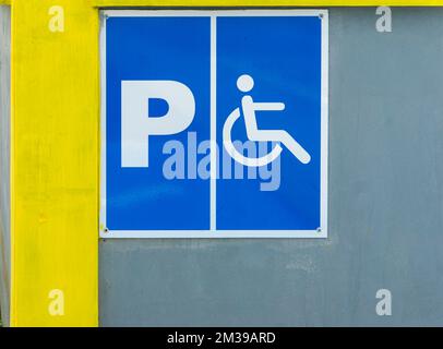 Schild für Behindertenparkplätze an der Betonwand eines öffentlichen Bereichs Stockfoto