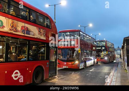 LONDON, GROSSBRITANNIEN - 9. Dezember 2022: Ein roter Bus auf der Rainy Street bei Nacht Stockfoto