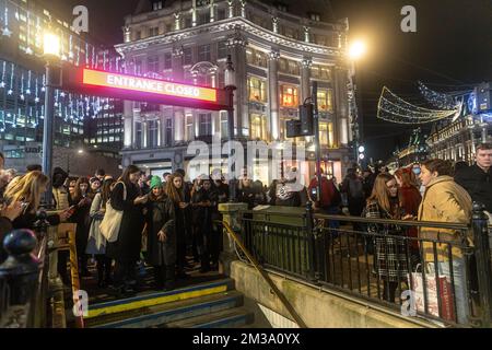 London, UK - 2. Dezember 2022: Menschen stehen in der Schlange, um die Oxford Street Metro während der Hauptverkehrszeit nach der Arbeit zu betreten Stockfoto