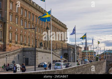 Wunderschöner Blick auf die schwedischen Nationalflaggen an der Fassade des Königspalastes und den bewölkten Hintergrund des Himmels. Schweden. Stockholm. Stockfoto