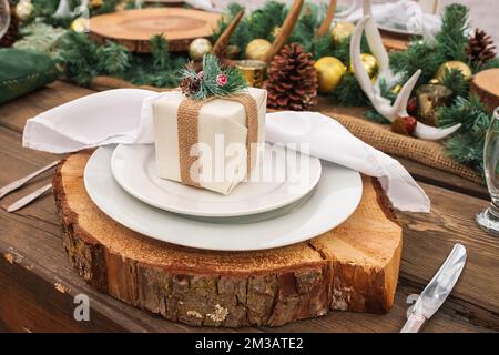 Rustikaler weihnachtlicher Serviertisch. Schöne Tischgestaltung mit Weihnachtsdekorationen im Wohnzimmer. Weihnachtsessen, Partydesign, Konzept - Tischset Stockfoto