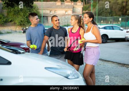 Zwei Tennisspielerpaare diskutieren gerne das letzte Spiel auf dem Parkplatz Stockfoto