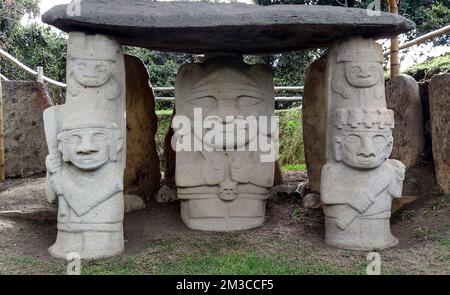 Ein alter Dolmen mit einem Priester oder chaman, der ein menschliches Herd mit zwei Kriegern auf beiden Seiten hält, im kolumbianischen archäologischen Park San Agustin. Stockfoto