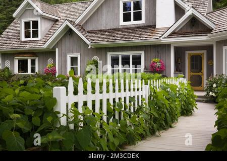 New Hampton Cottage-Stil Haus mit landschaftlich gestaltetem Vorgarten und Holzsteg im Sommer, Quebec, Kanada. Dieses Bild ist Eigentum freigegeben. CUPR0208 Stockfoto